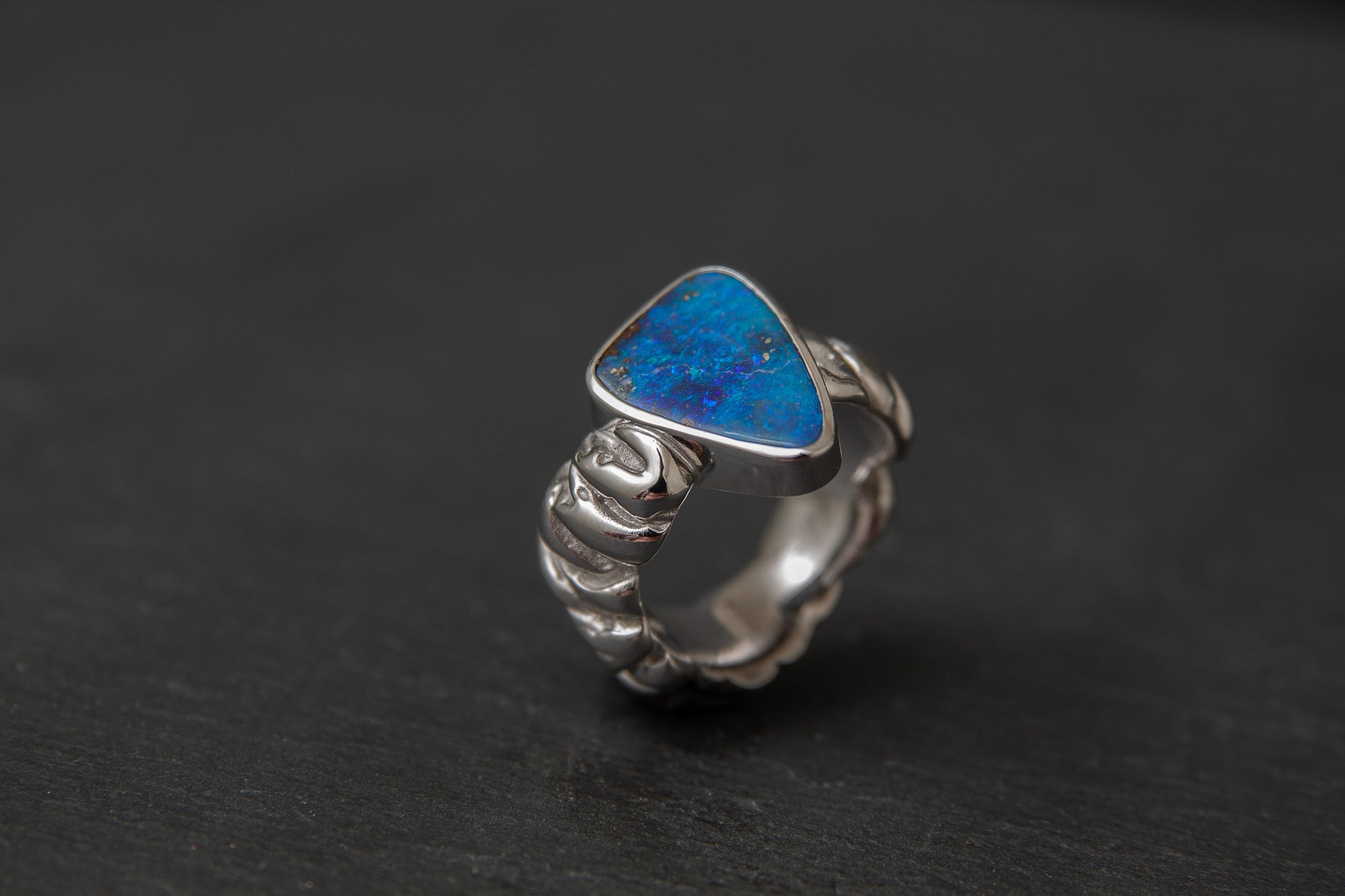 Ring aus Weissgold 750 mit strukturierter Schiene und einem farbintensiven Boulderopal als Mittelstein.