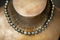 Dunkelgrün-graues Tahitiperlen-Collier mit gerillten Perlen und Wechselschließe aus Stahl.