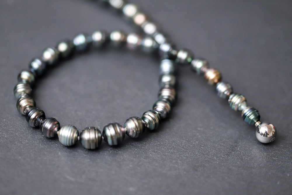 Dunkelgrün-graues Tahitiperlen-Collier mit gerillten Perlen und Wechselschließe aus Stahl.