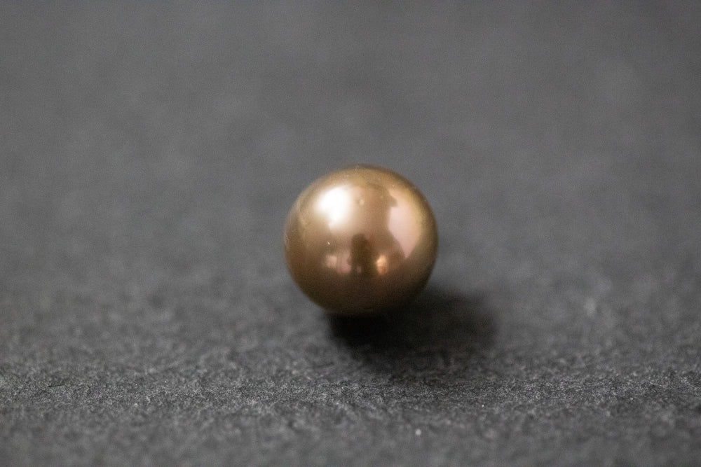 Runde Südseeperle in braun-goldenem Farbton mit starkem, metallischem Glanz