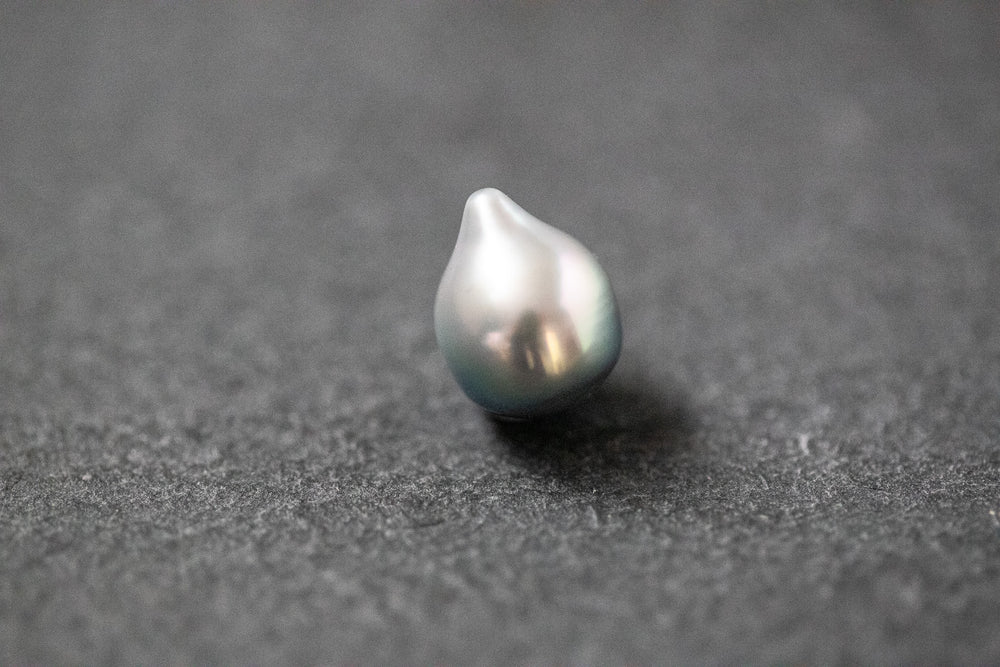 Einzelne Tahitiperle in hellgrauer Fantasieform mit feinem Lüster und organischer Oberfläche.