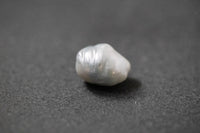 Hellgraue Frischwasserperle in unregelmässiger Fantasieform mit sanftem Lüster 