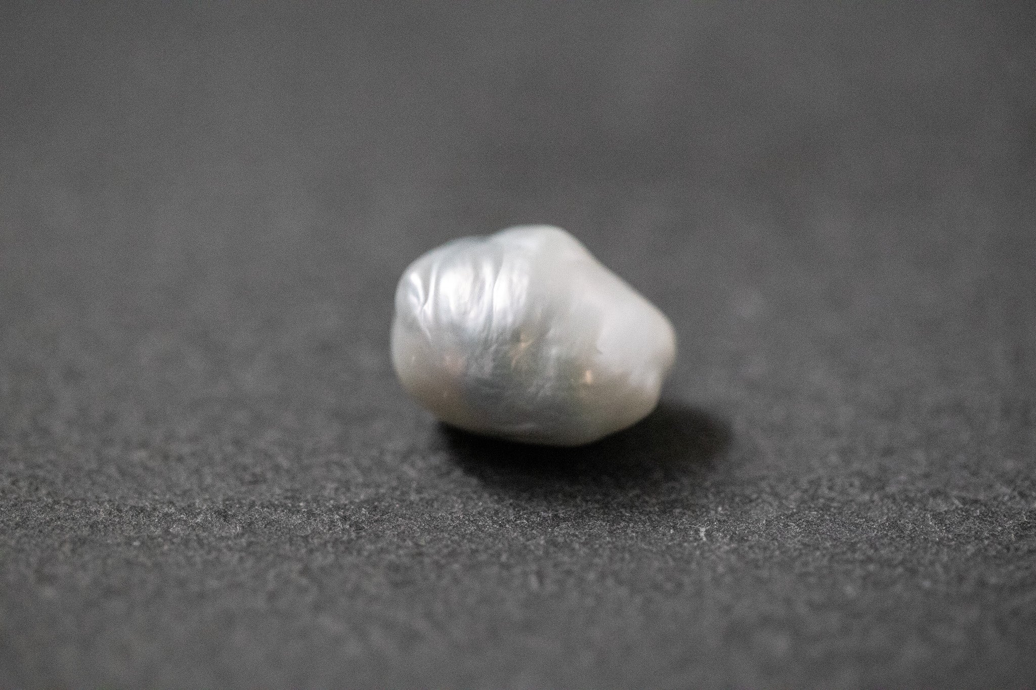 Hellgraue Frischwasserperle in unregelmässiger Fantasieform mit sanftem Lüster 