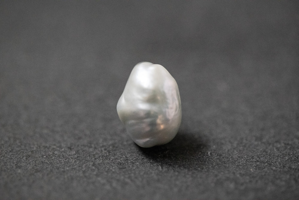 Hellgraue Frischwasserperle in unregelmässiger Fantasieform mit sanftem Lüster 