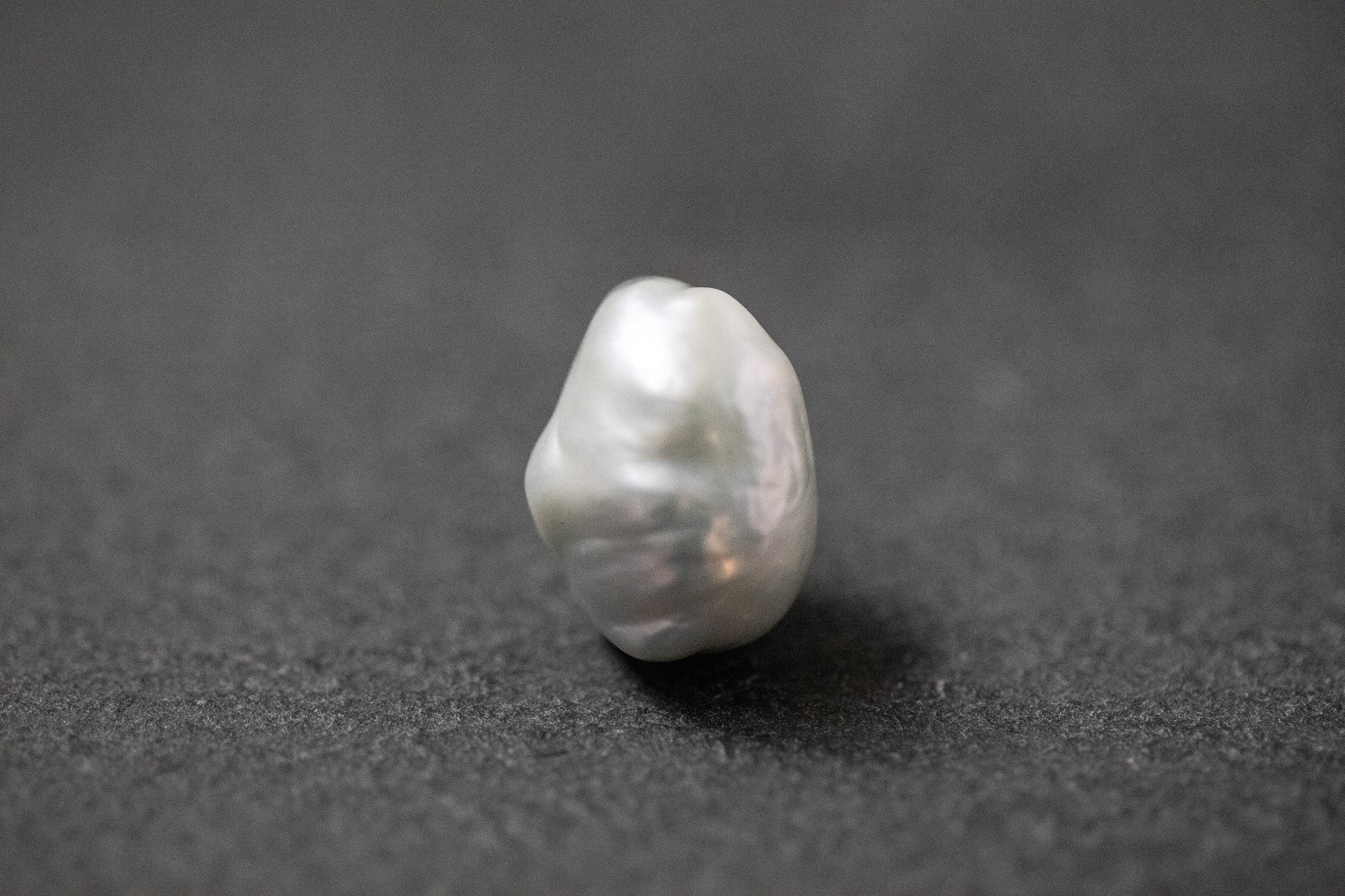 Hellgraue Frischwasserperle in unregelmässiger Fantasieform mit sanftem Lüster 