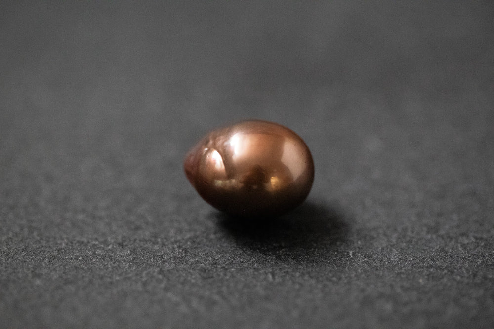 Oval geformte Frischwasserperle in warmem Schokoladenbraun mit glänzender Oberfläche