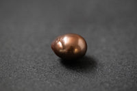 Oval geformte Frischwasserperle in warmem Schokoladenbraun mit glänzender Oberfläche