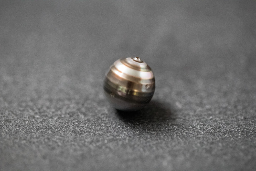 Oval geformte Tahitiperle mit fließendem Grau-Verlauf und seidig schimmernder Oberfläche