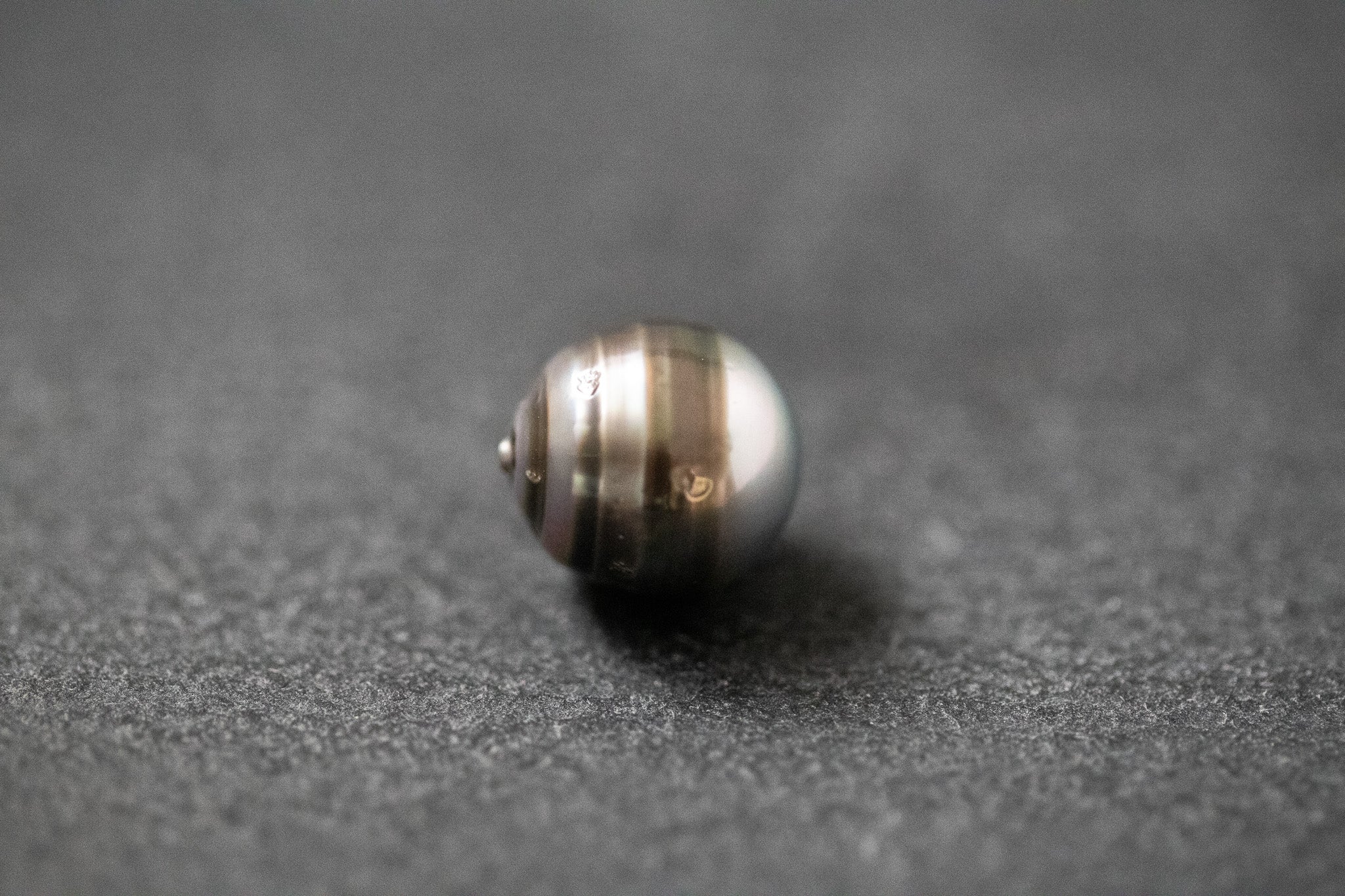 Oval geformte Tahitiperle mit fließendem Grau-Verlauf und seidig schimmernder Oberfläche