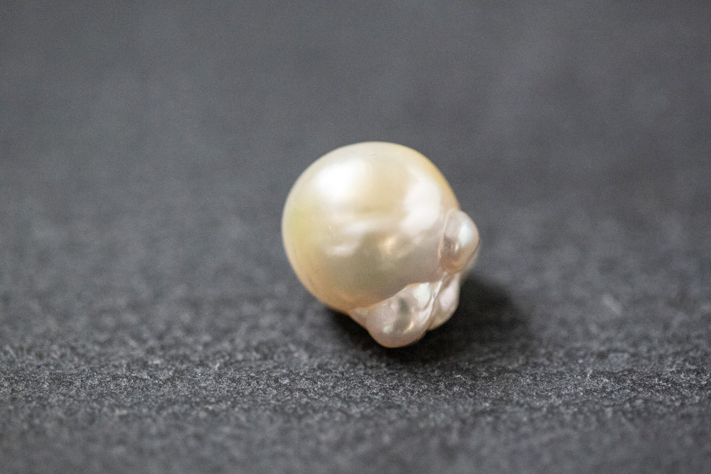 Barocke Frischwasserperle mit unregelmäßiger Form und schimmerndem Farbverlauf in Gelb und Weiss