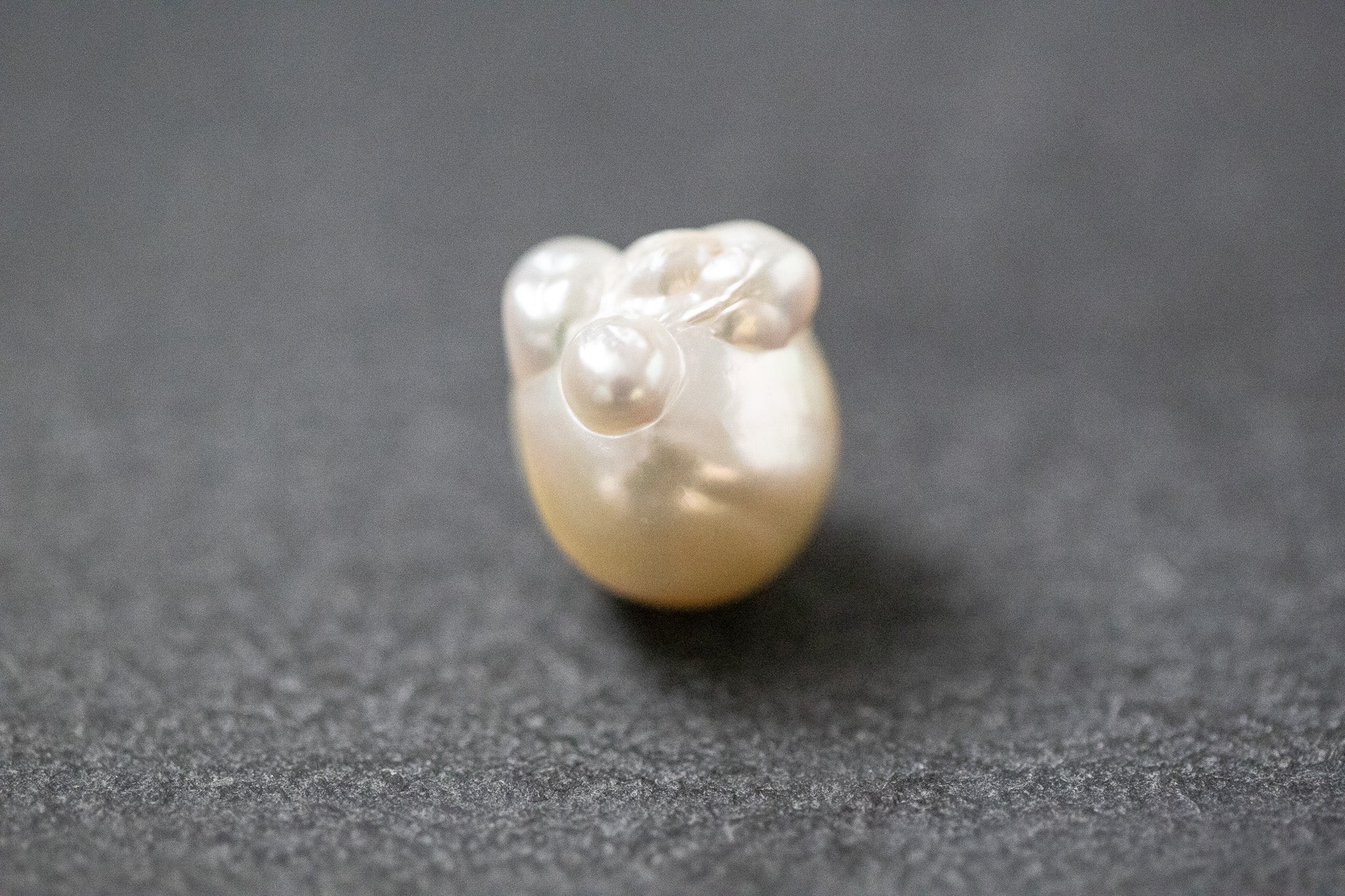 Barocke Frischwasserperle mit unregelmäßiger Form und schimmerndem Farbverlauf in Gelb und Weiss