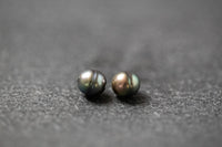 Zwei ovale, gerillte Tahitiperlen in schimmerndem Grau-Grün mit natürlicher Struktur.