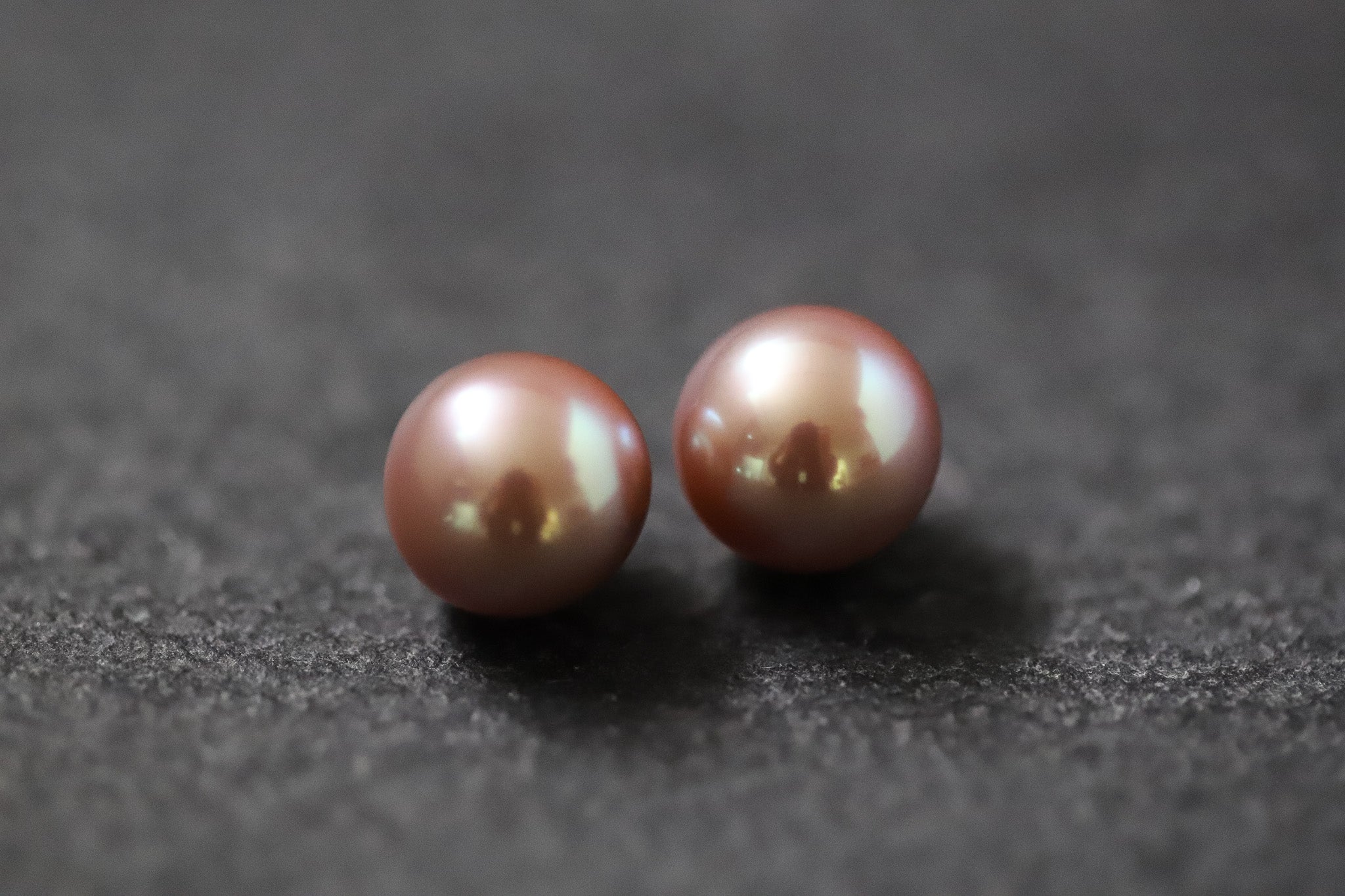Zwei runde Frischwasserperlen in Dunkelrosa mit zartem Glanz auf hellem Untergrund – ideal für handgefertigten Schmuck.