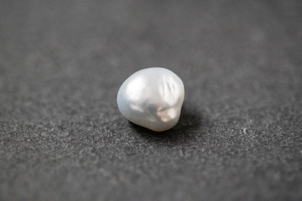 Frischwasserperle in hellgrauer Fantasieform mit natürlicher Struktur und sanftem Glanz.