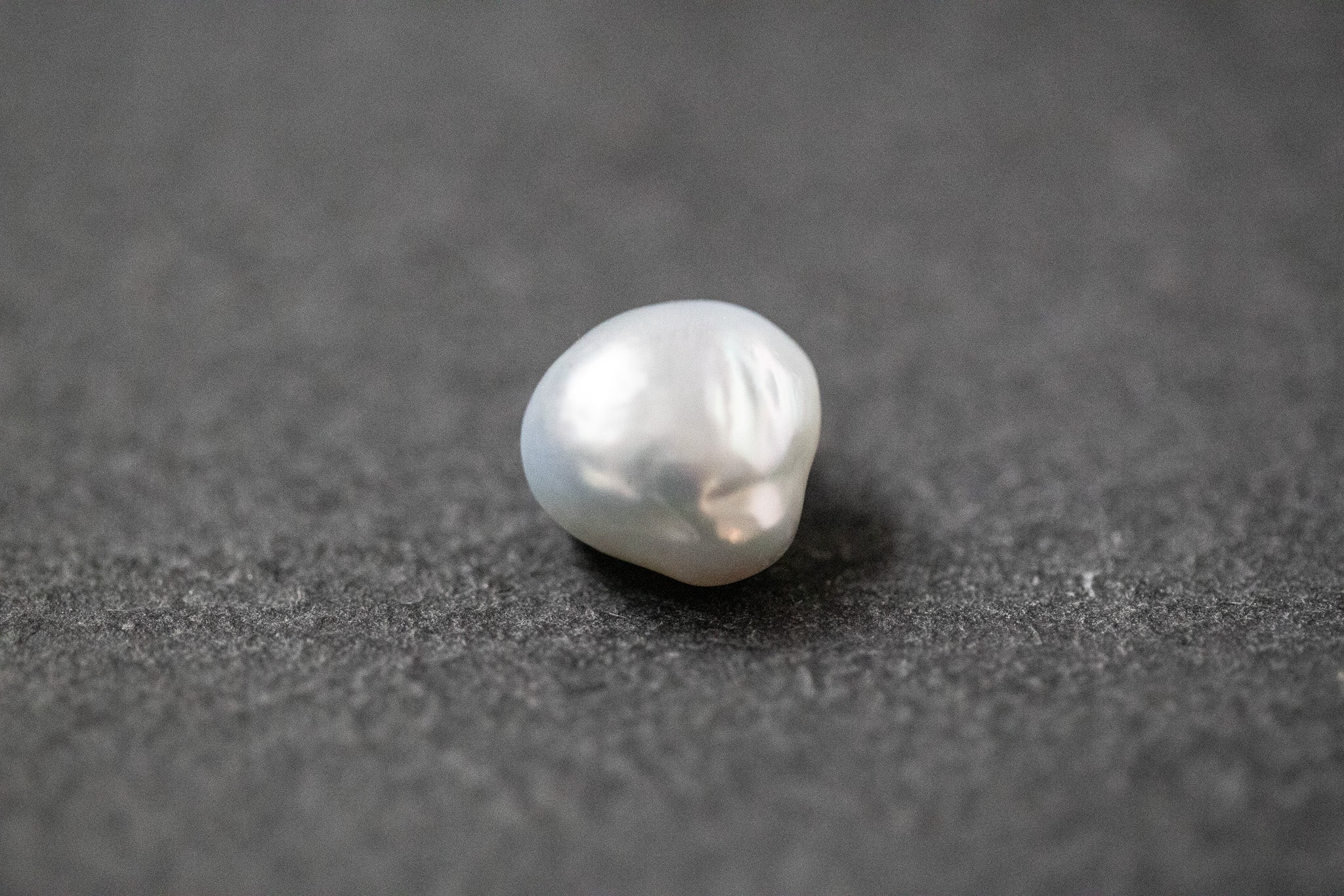 Frischwasserperle in hellgrauer Fantasieform mit natürlicher Struktur und sanftem Glanz.